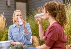 Dames die water drinken uit herbruikbare flessen